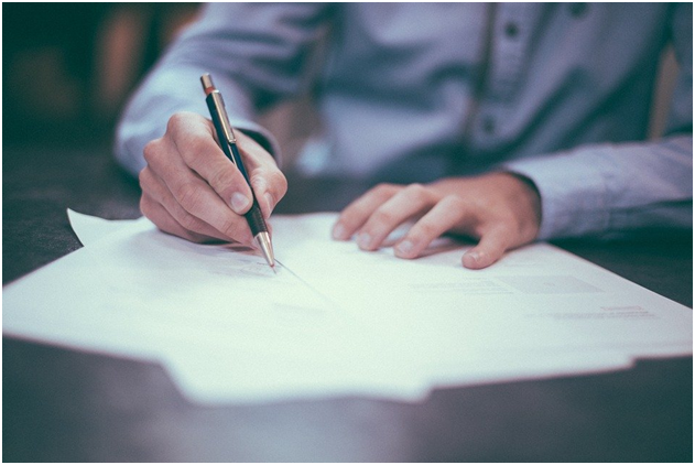 A person writing on paper with a pen